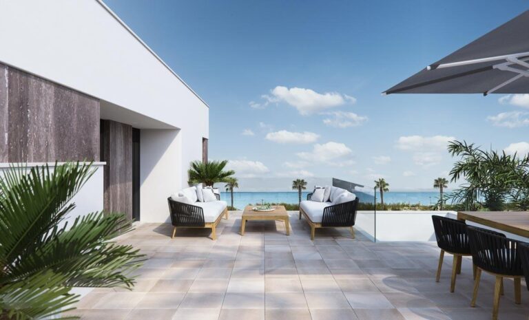 à propos de nous 3 Luxurious terrace with modern furniture overlooking the sea, featuring comfortable seating and a dining area under an umbrella.